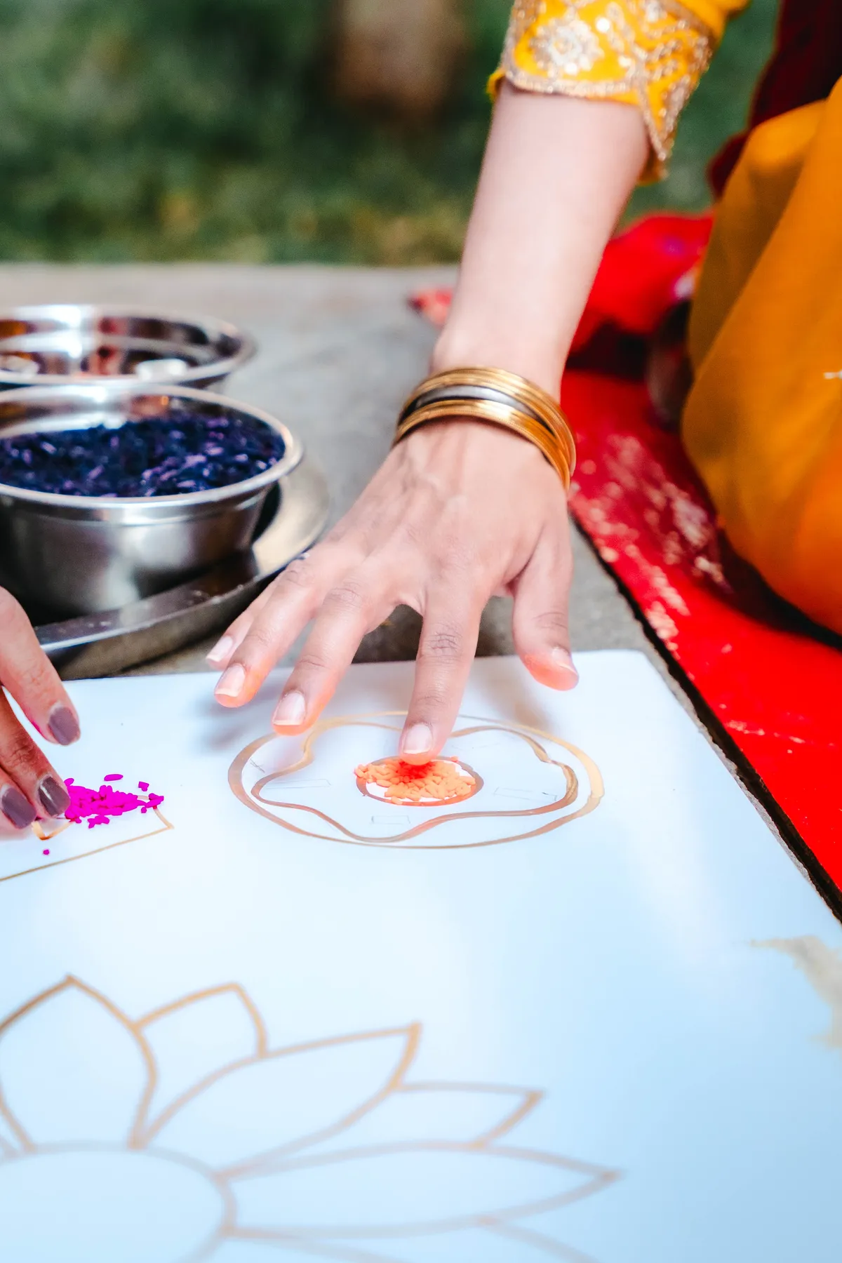 Hands creating colourful ceremonial artwork at Aaron’s Haldi celebration.