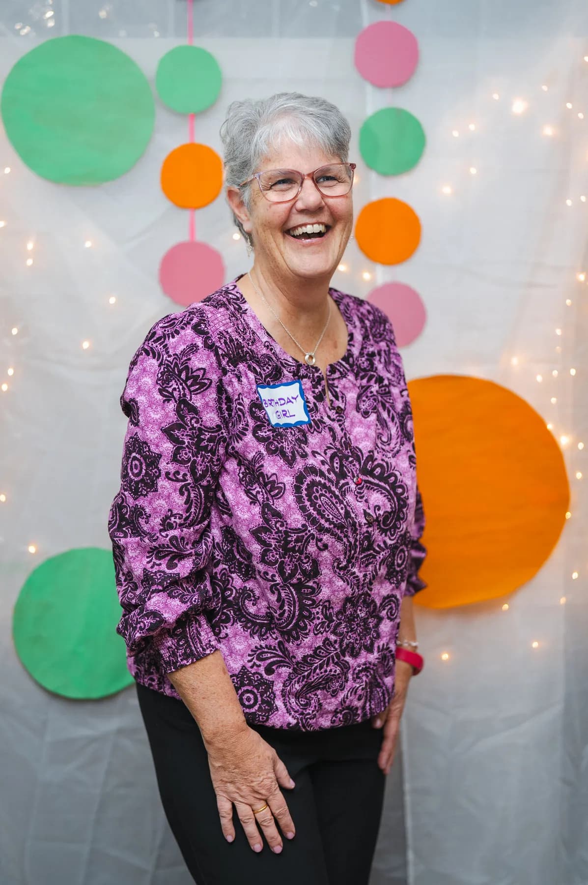 A woman posing in a purple floral outfit at Alison’s birthday celebration.