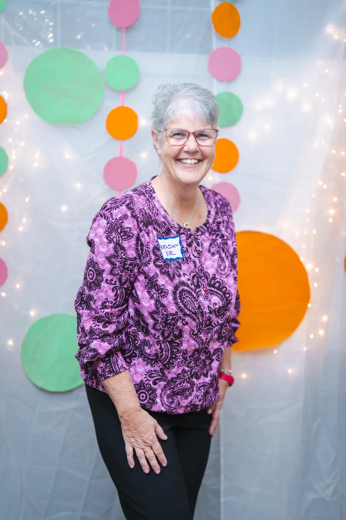 A woman posing in a purple floral outfit at Alison’s birthday celebration.