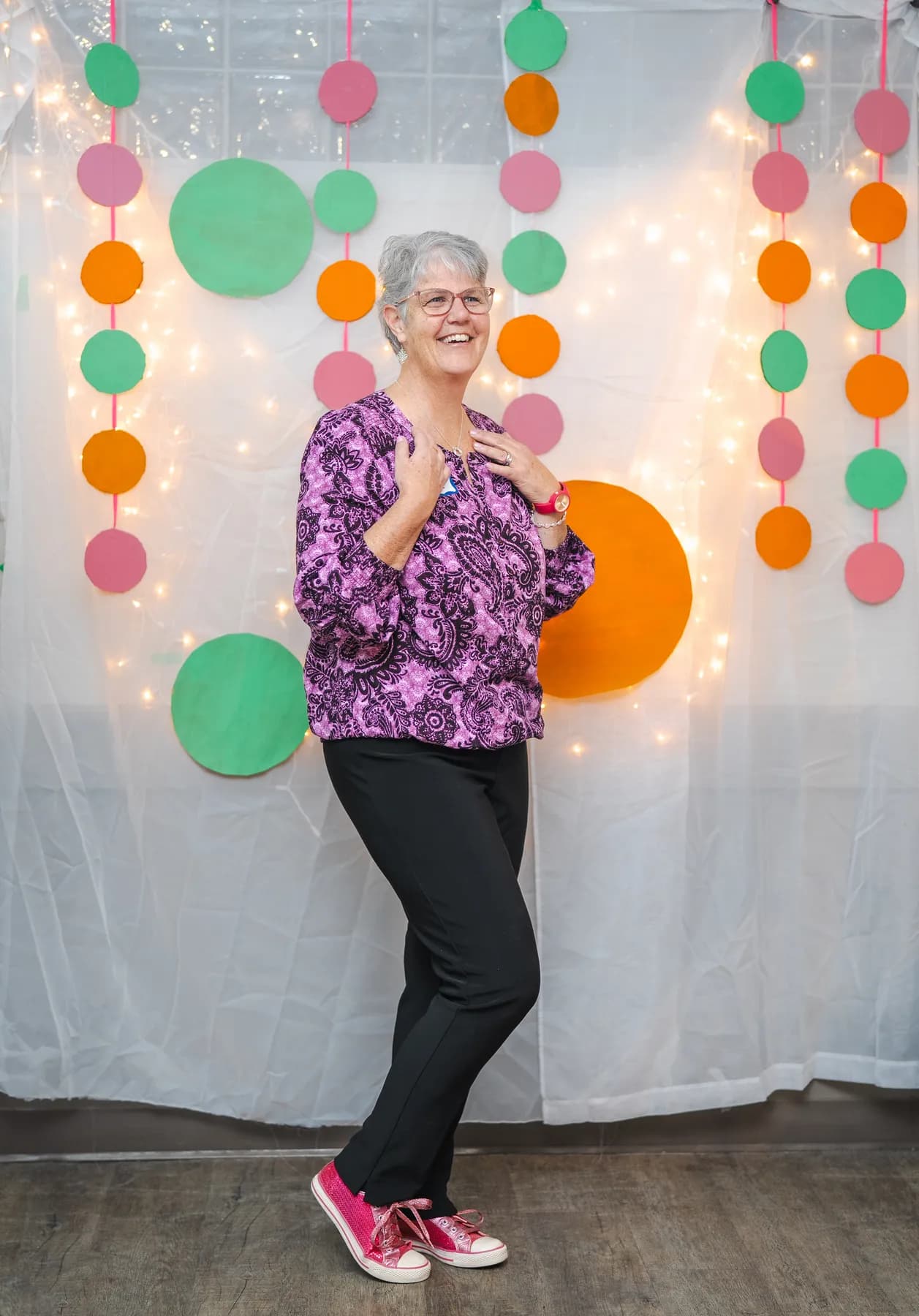 A woman posing in a purple floral outfit at Alison’s birthday celebration.