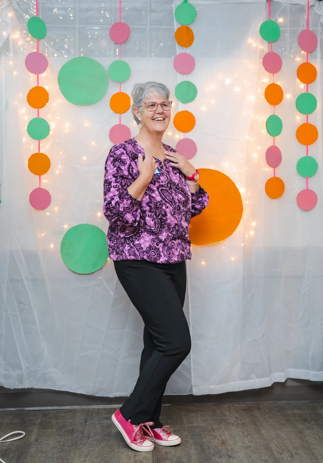 A woman posing in a purple floral outfit at Alison’s birthday celebration.