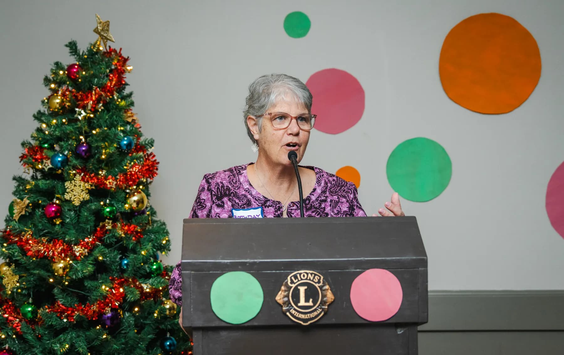 A woman speaking at the lectern at Alison’s birthday celebration.