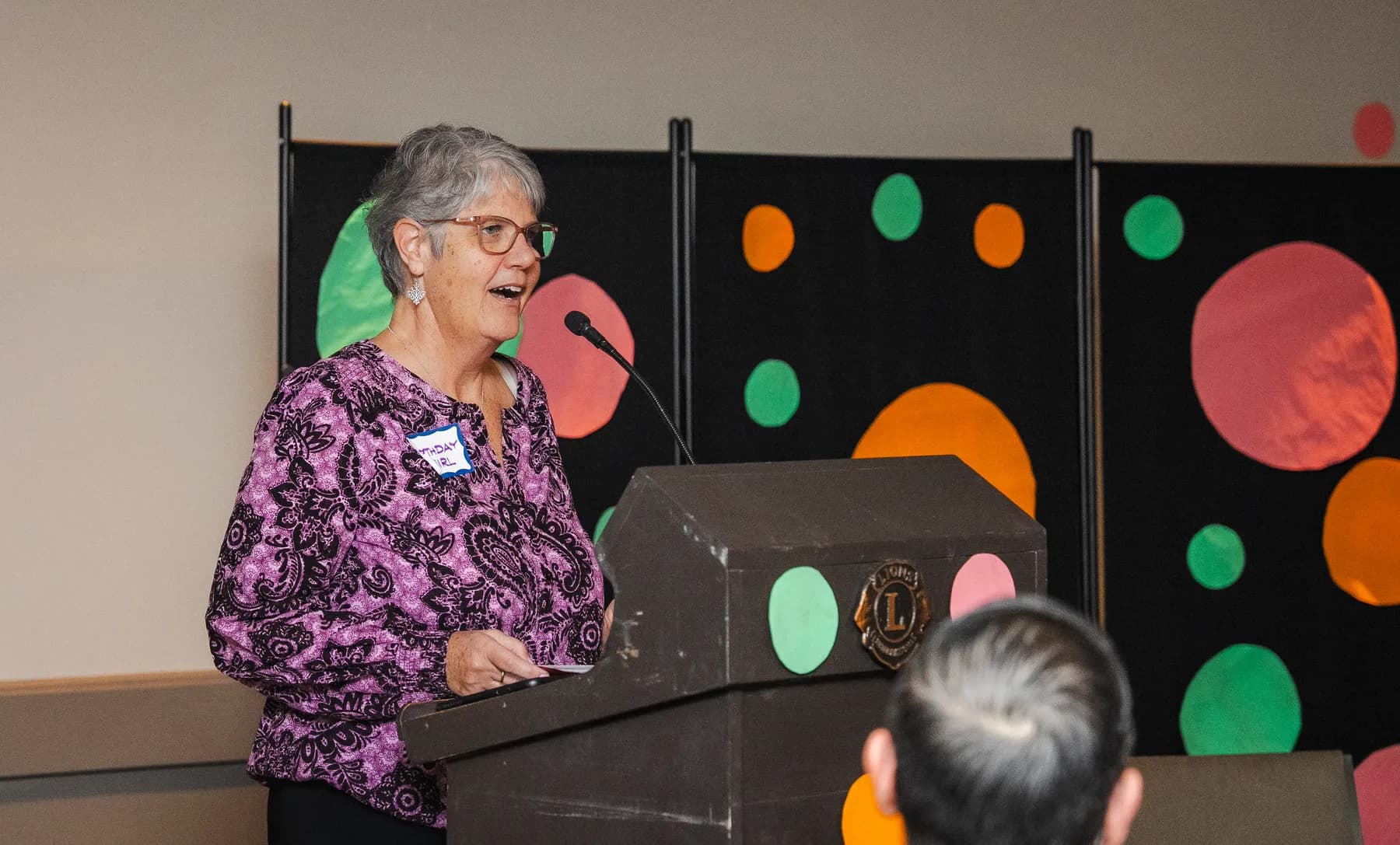A woman speaking at the lectern at Alison’s birthday celebration.