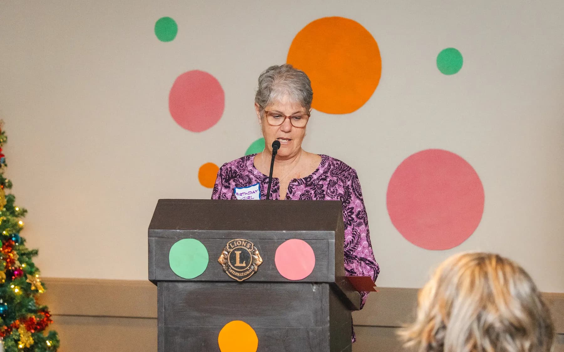A woman speaking at the lectern at Alison’s birthday celebration.
