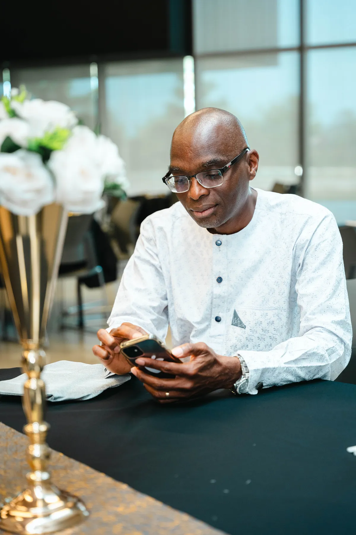 A seated guest looking at a phone at BJ’s 40th birthday party.
