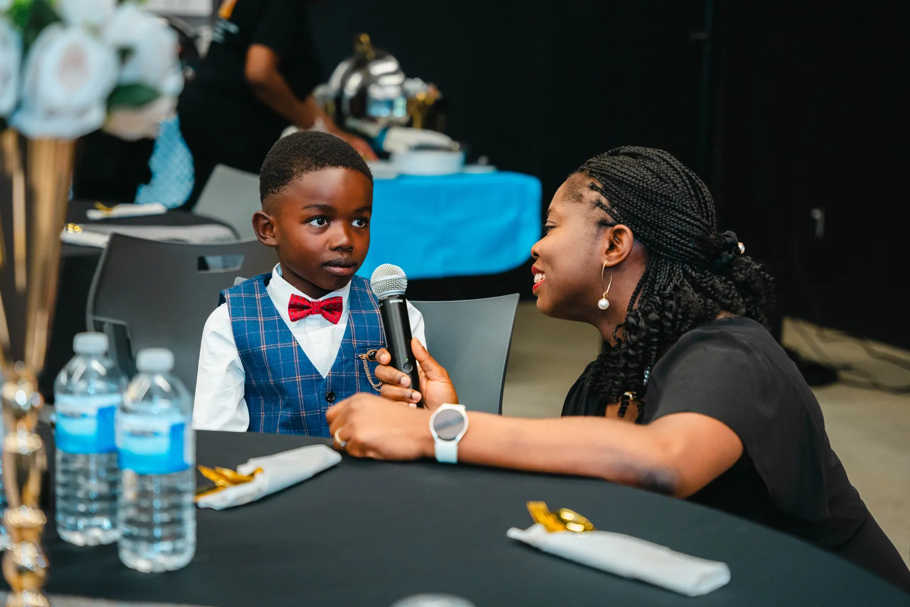 A child with a microphone at a table at BJ’s 40th birthday party.