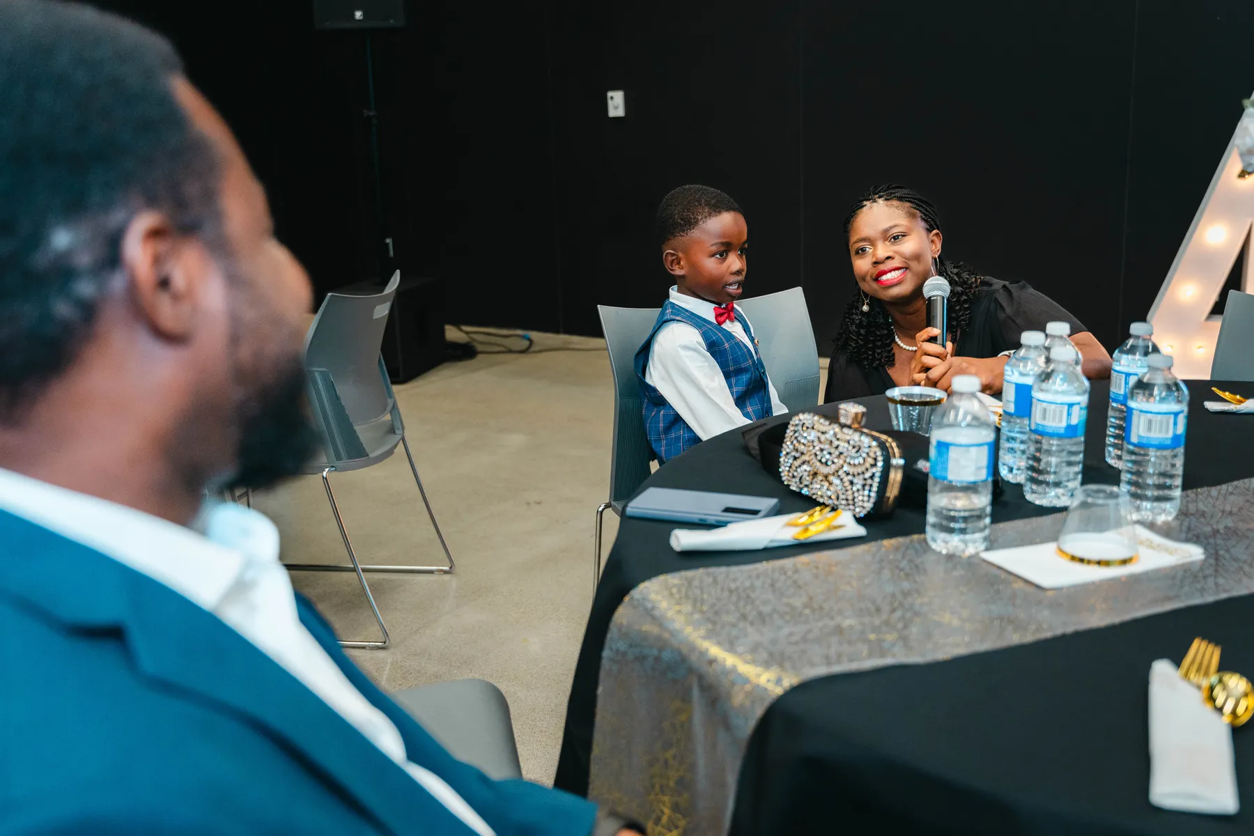 A child with a microphone at a table at BJ’s 40th birthday party.