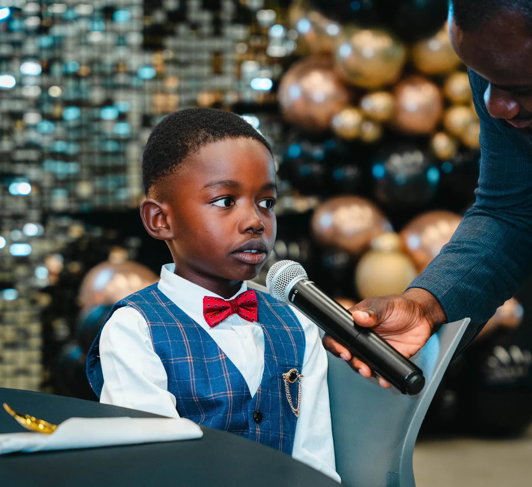 A child speaking into a microphone at BJ’s 40th birthday party.