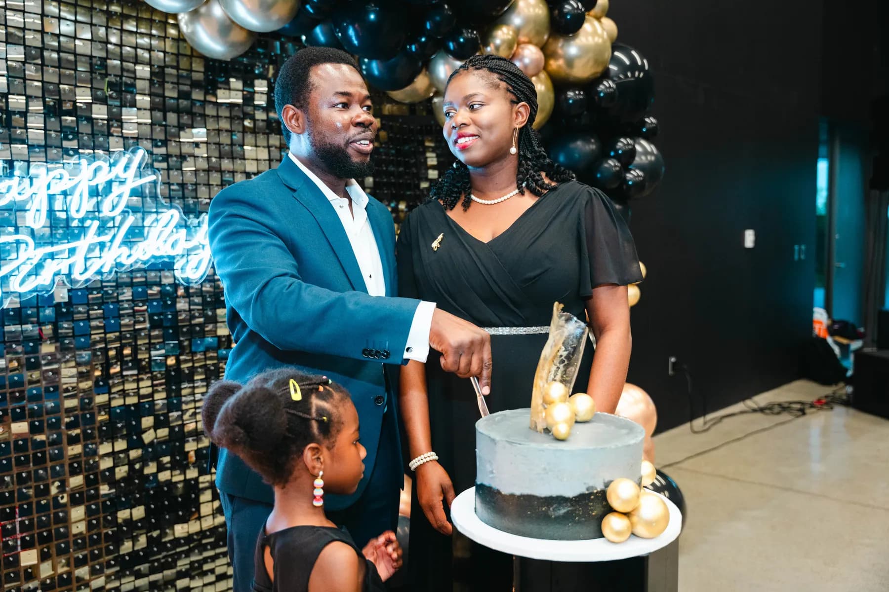 A couple cutting the cake with a child beside them at BJ’s 40th birthday party.