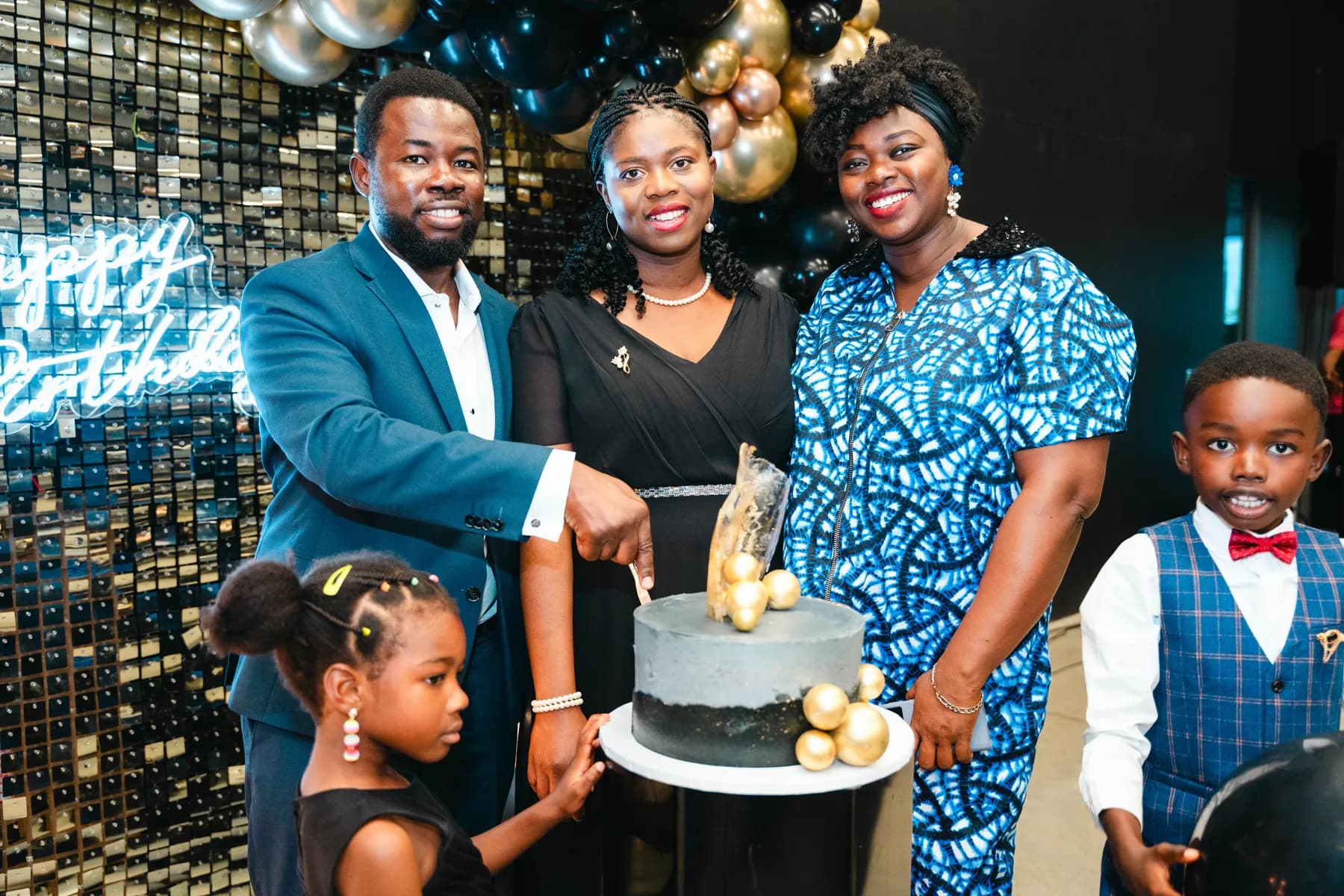 A couple cutting the cake with a child beside them at BJ’s 40th birthday party.