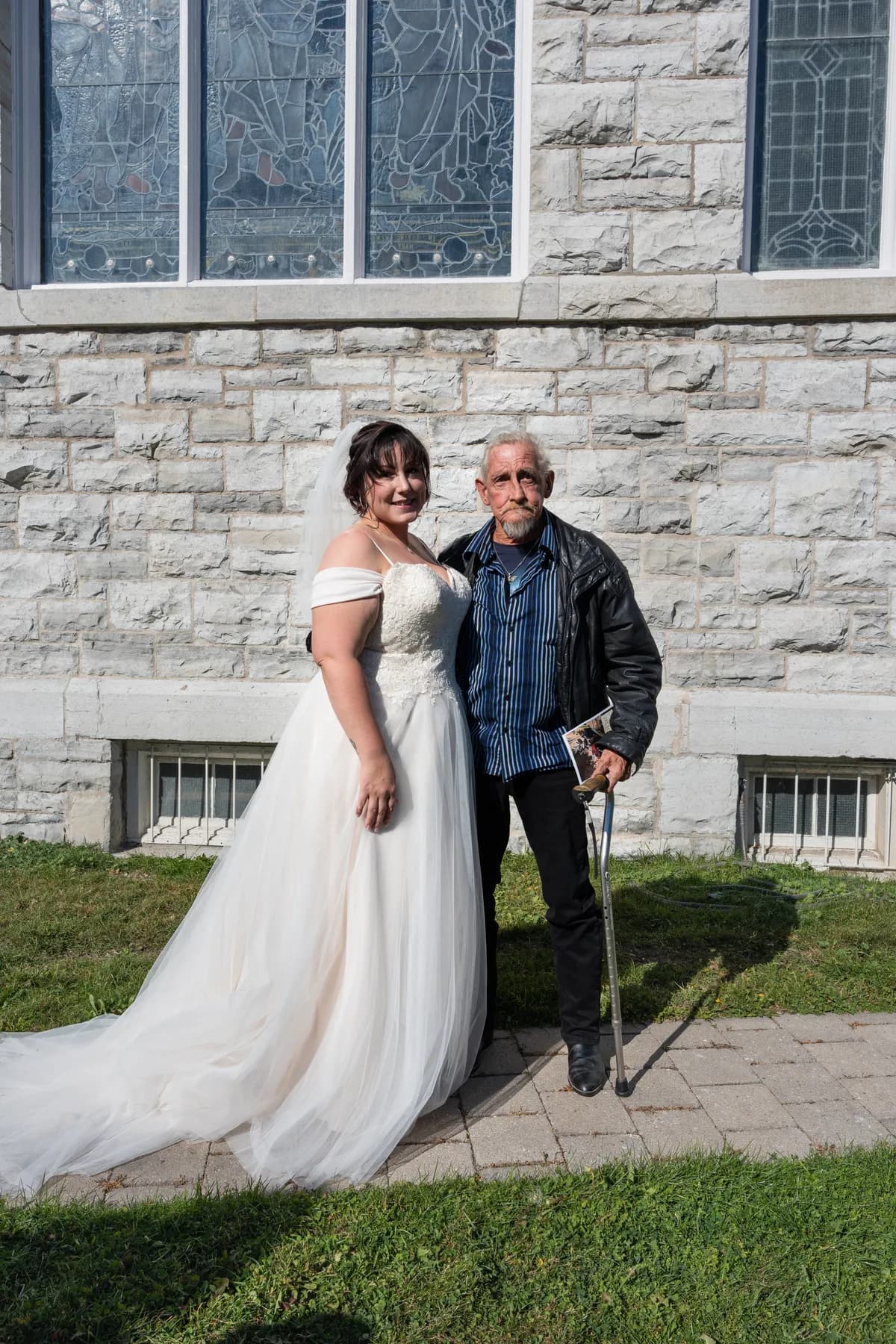The bride posing with a male guest outside the church at Kody and Jaz’s wedding.