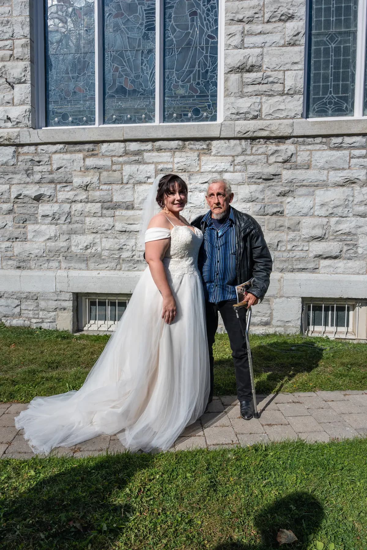 The bride posing with a male guest outside the church at Kody and Jaz’s wedding.