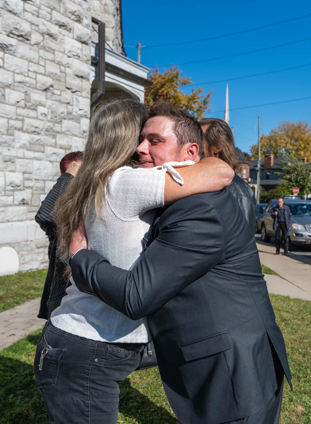 Guests hugging outside the church at Kody and Jaz’s wedding.
