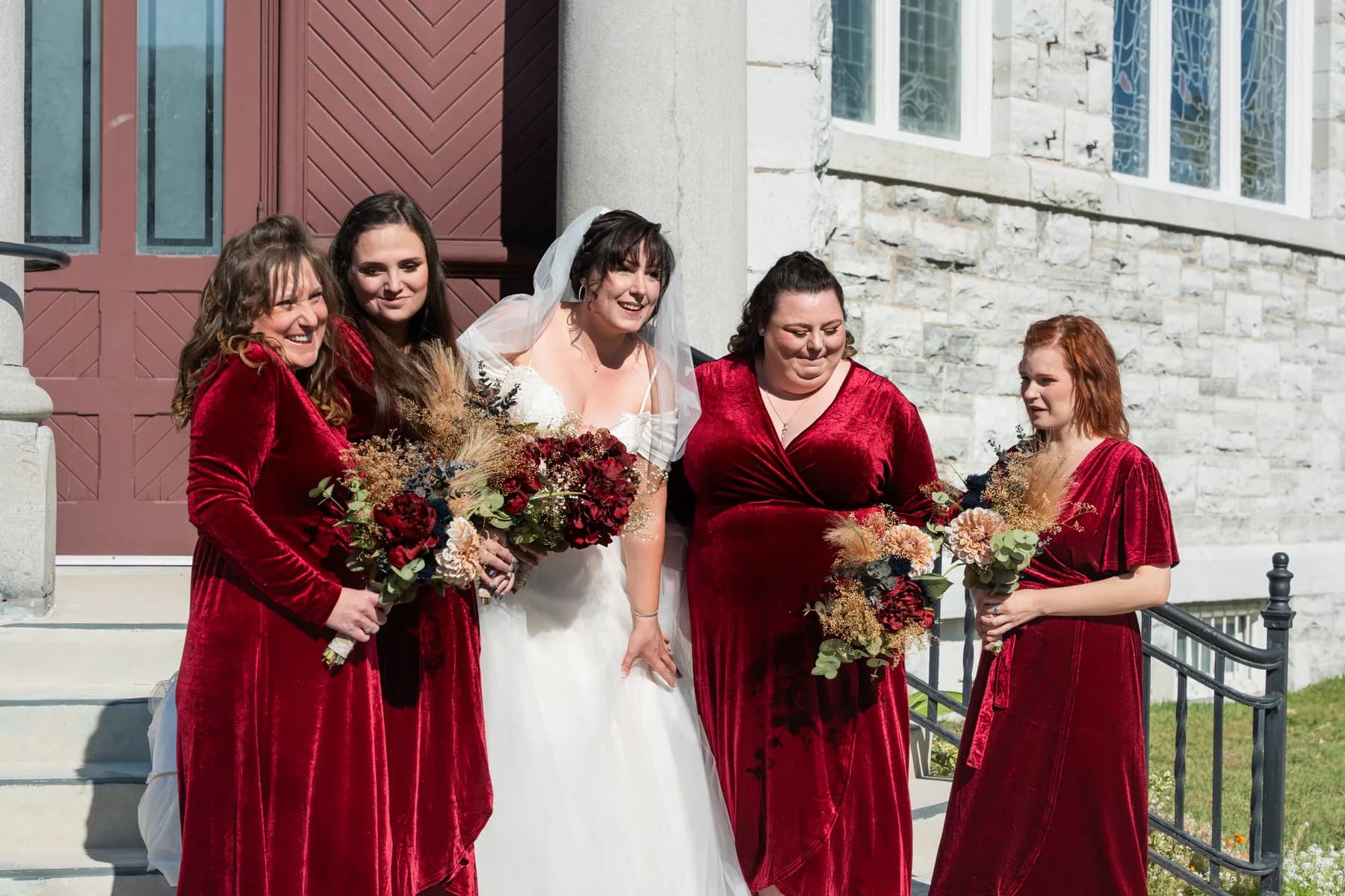 The bride with bridesmaids and a flower girl outside the church at Kody and Jaz’s wedding.
