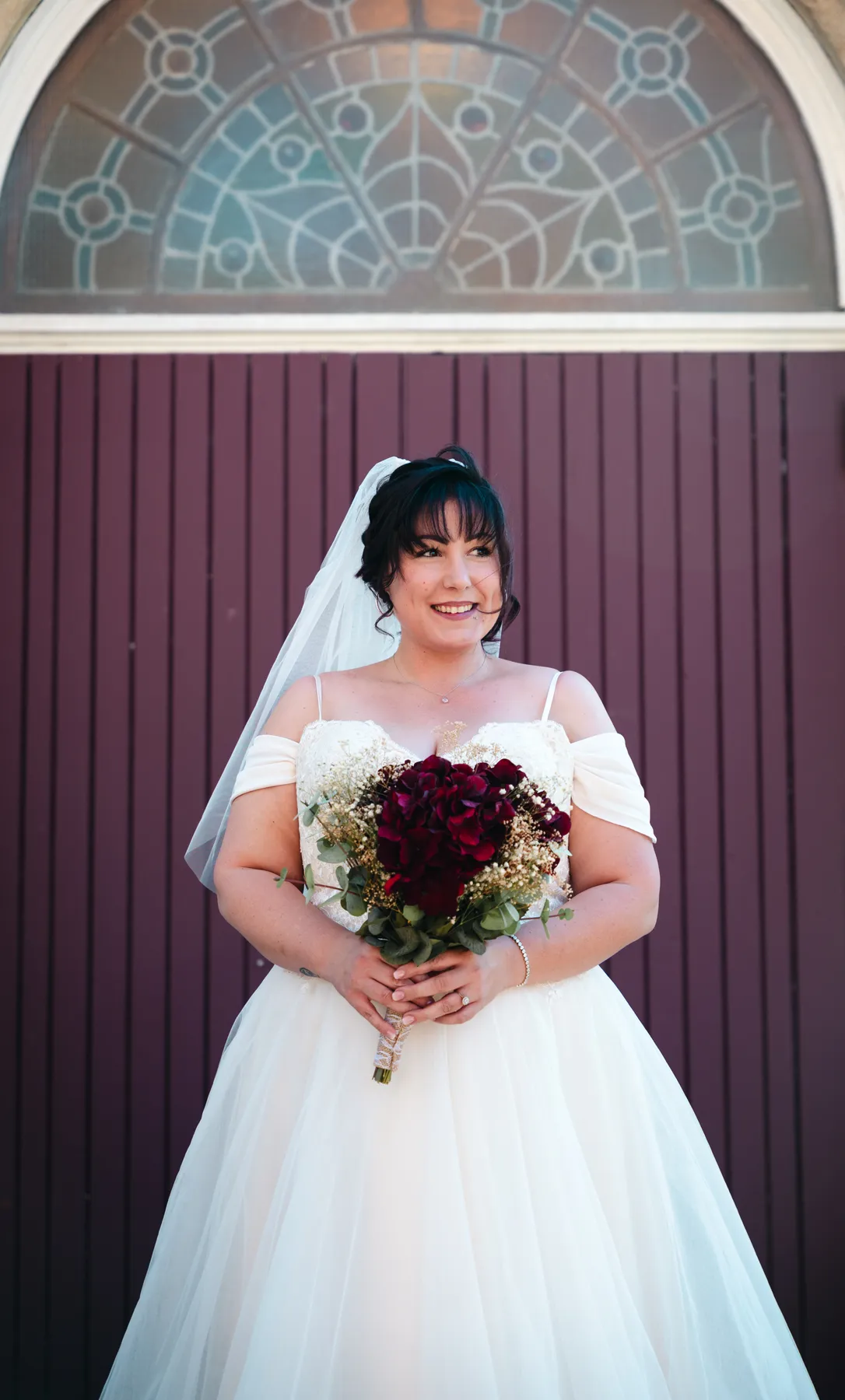 The bride posing at the red church door at Kody and Jaz’s wedding.
