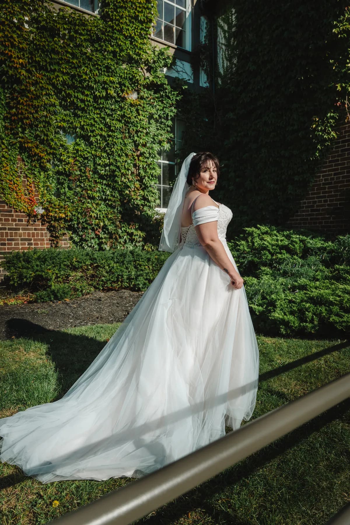The bride posing in a garden with her gown trailing behind at Kody and Jaz’s wedding.