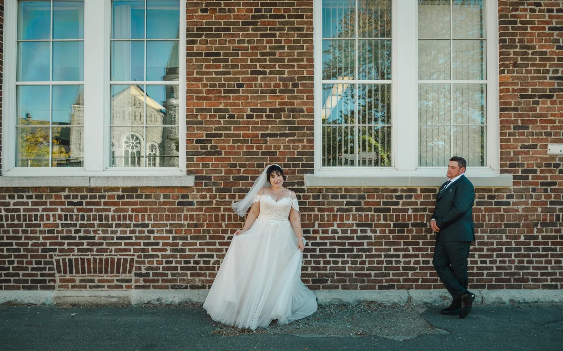 The couple walking and posing beside a brick wall at Kody and Jaz’s wedding.