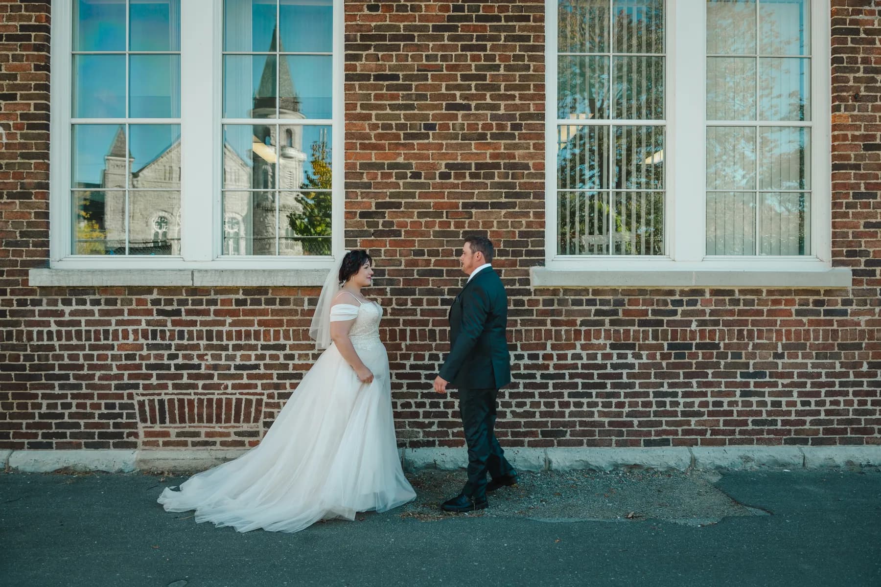 The couple walking and posing beside a brick wall at Kody and Jaz’s wedding.