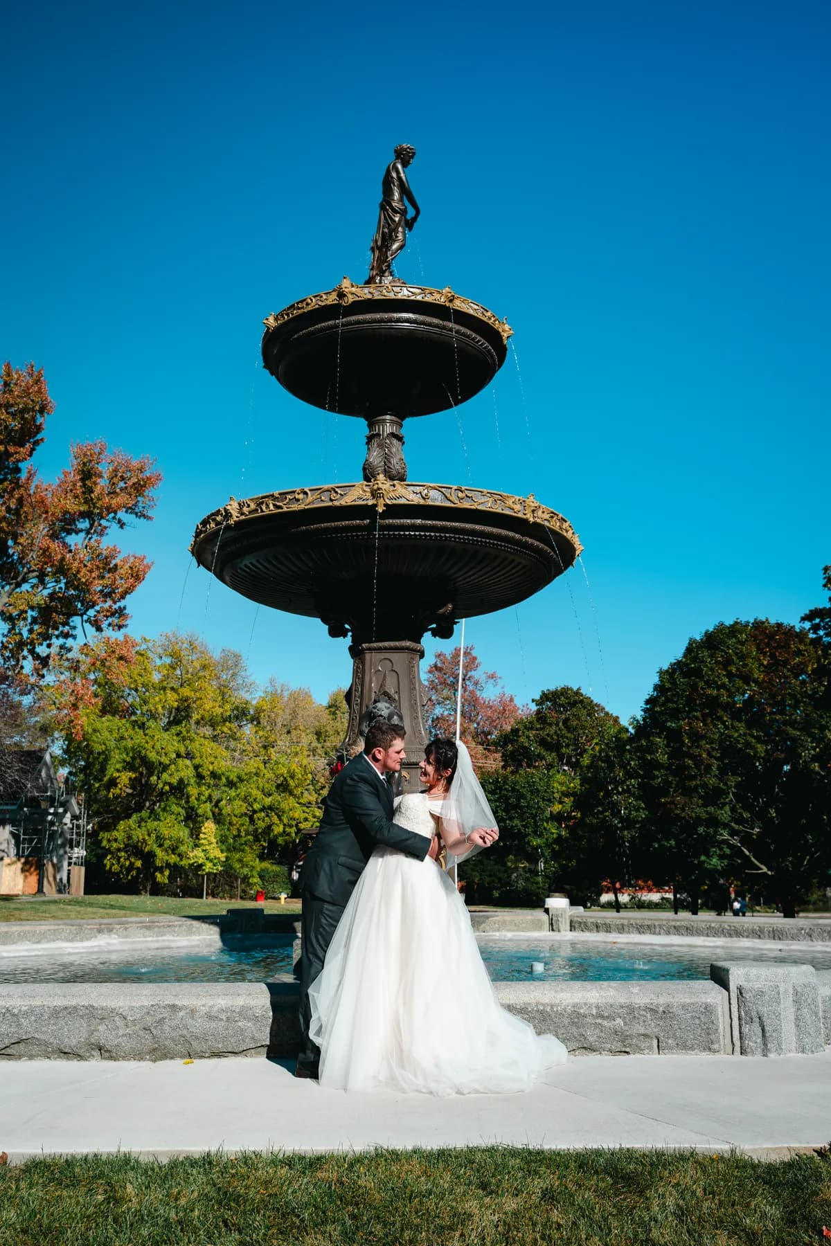 The couple posing by a large fountain at Kody and Jaz’s wedding.