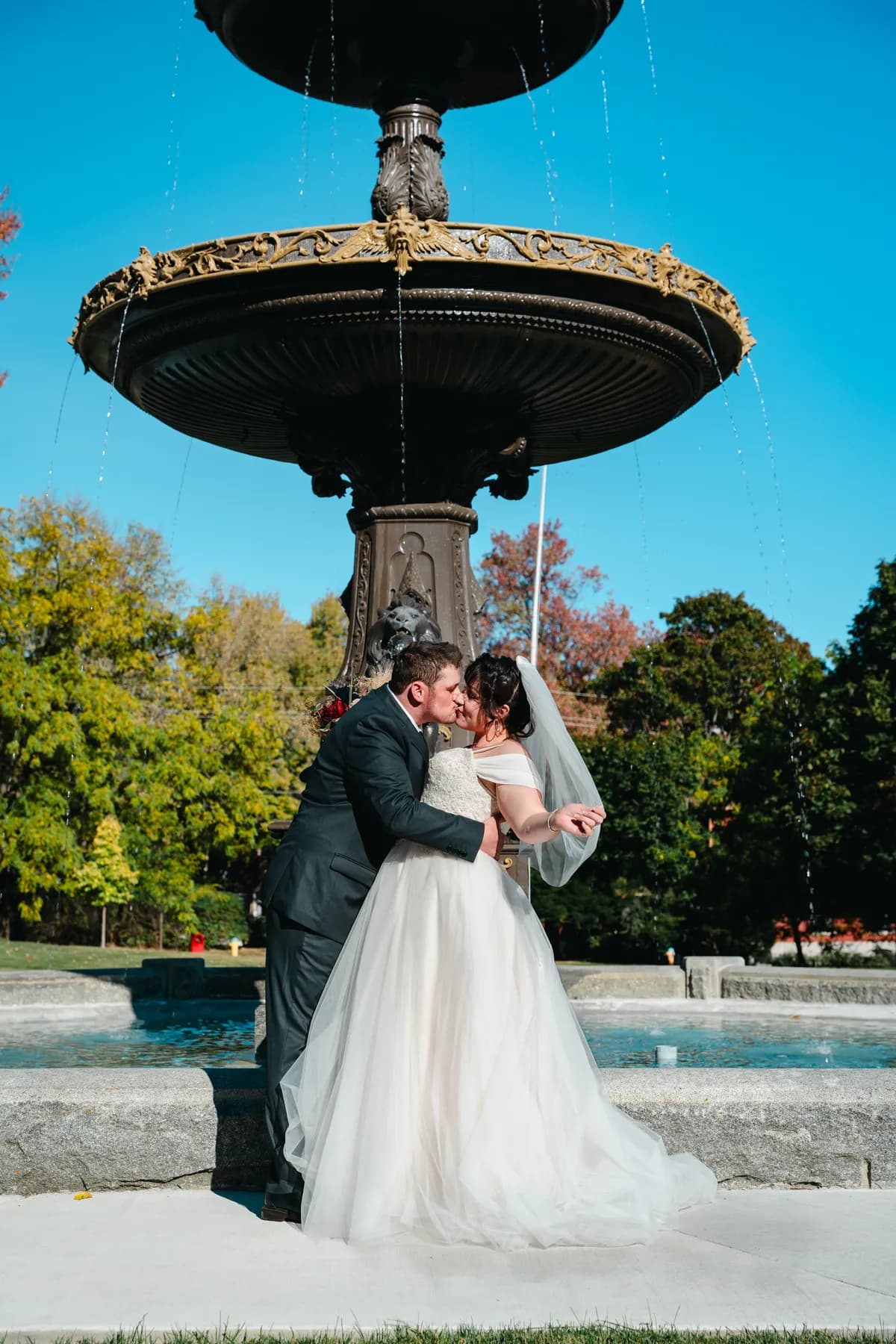 The couple posing by a large fountain at Kody and Jaz’s wedding.