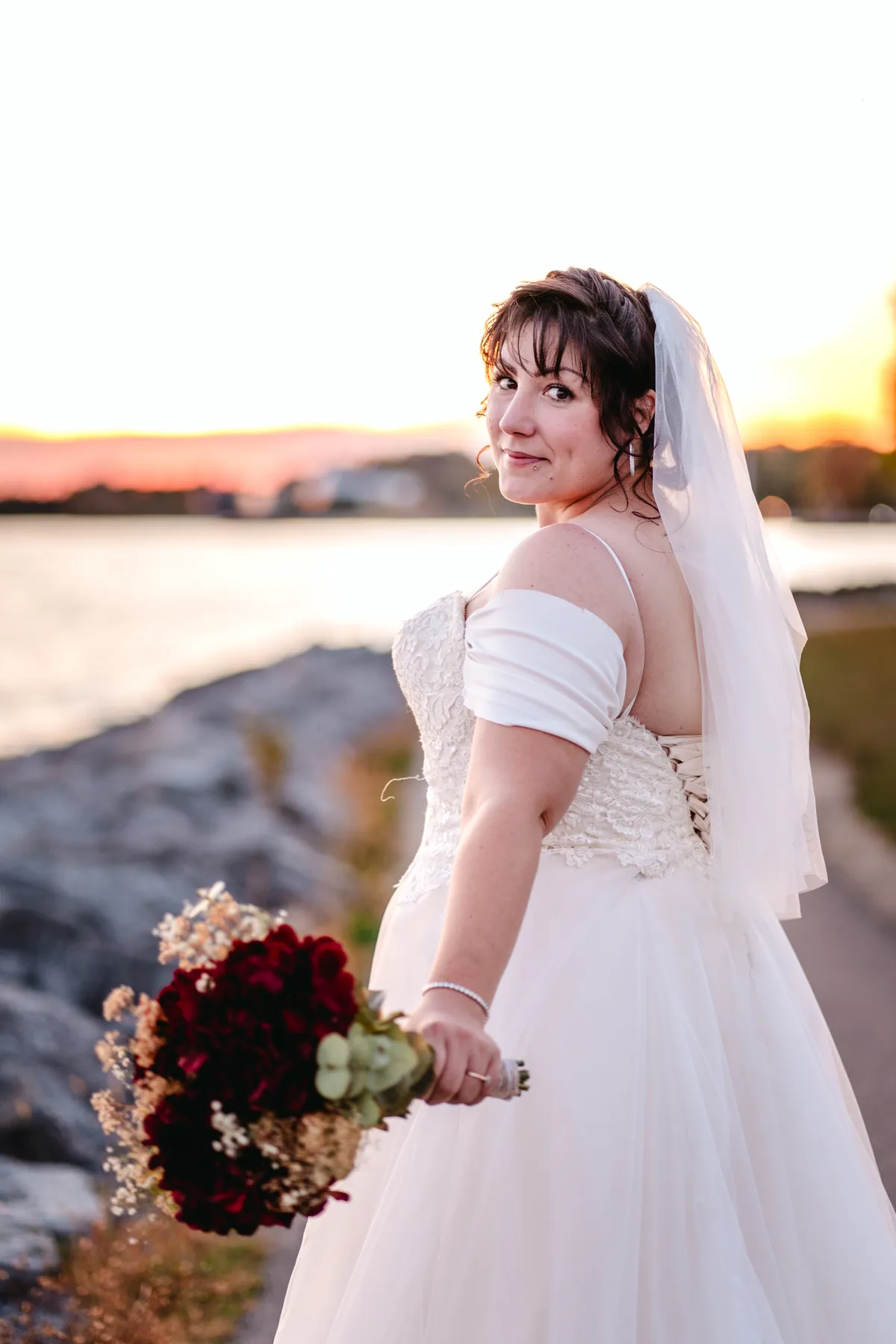 The bride posing by the water at sunset at Kody and Jaz’s wedding.