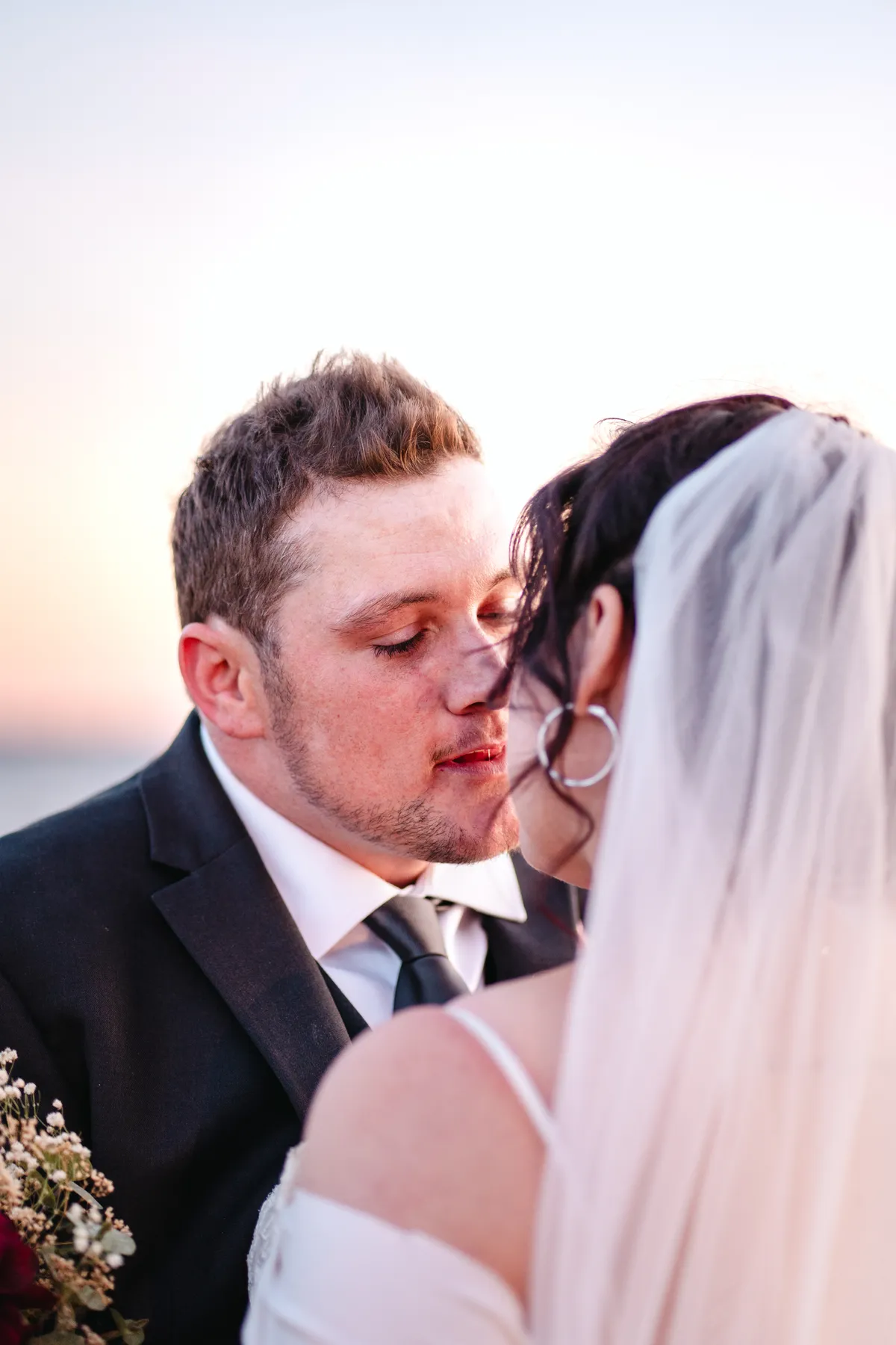 The couple posing by the water at sunset at Kody and Jaz’s wedding.