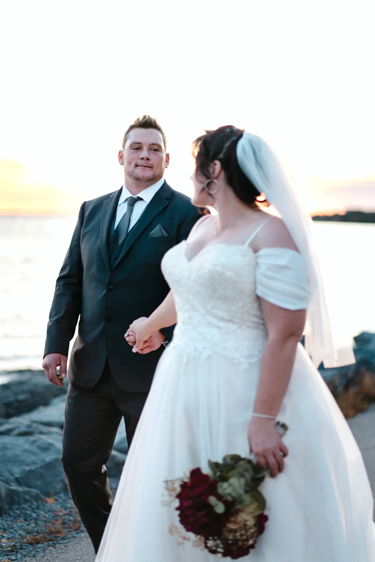 The couple posing by the water at sunset at Kody and Jaz’s wedding.