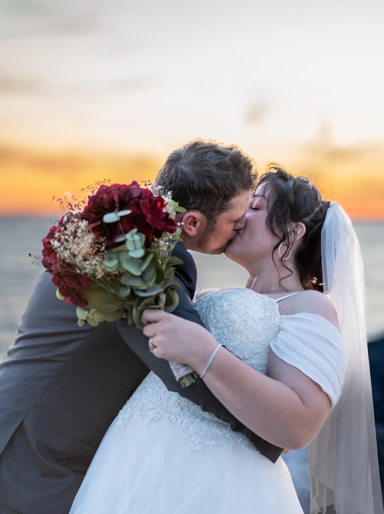 The couple kissing by the water at sunset at Kody and Jaz’s wedding.