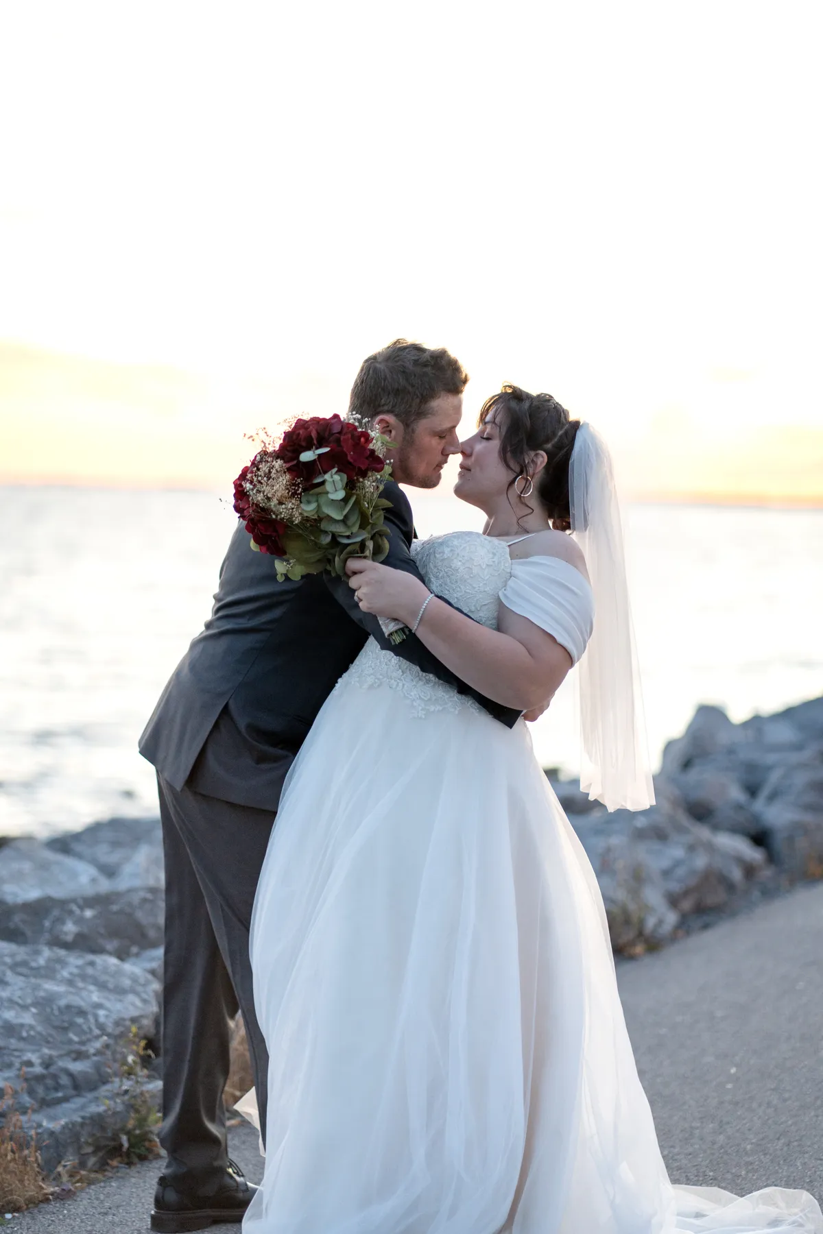 The couple kissing by the water at sunset at Kody and Jaz’s wedding.