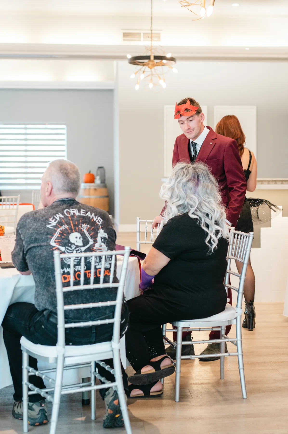 Guests mingling indoors with Halloween table decorations at Jenna and Jake’s Halloween party.