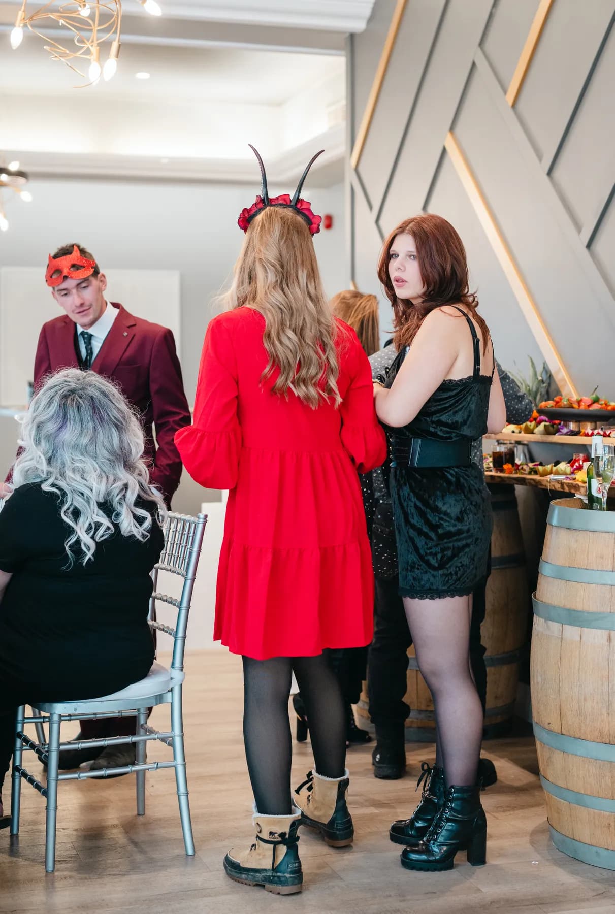 Guests mingling indoors with Halloween table decorations at Jenna and Jake’s Halloween party.