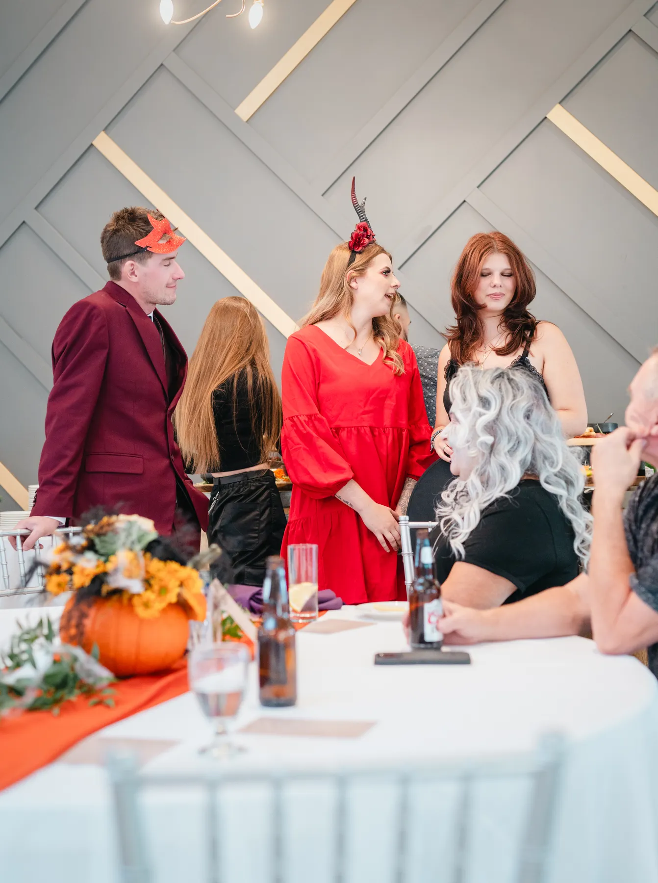Guests mingling indoors with Halloween table decorations at Jenna and Jake’s Halloween party.