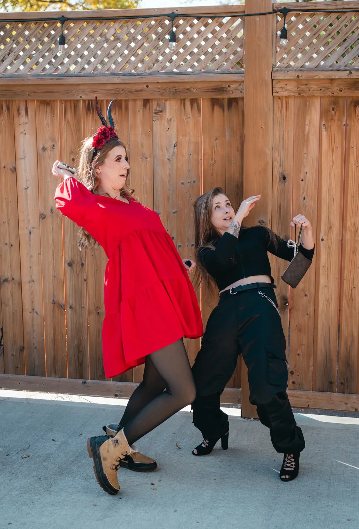 Two women dancing and posing in the outdoor courtyard at Jenna and Jake’s Halloween party.