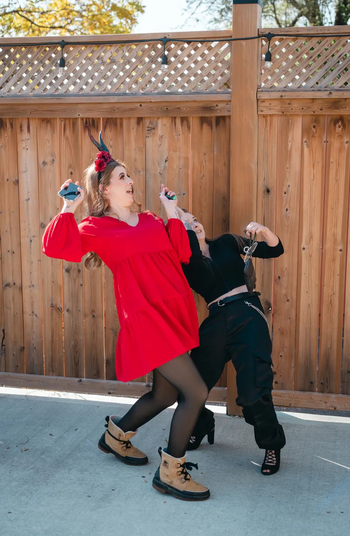 Two women dancing and posing in the outdoor courtyard at Jenna and Jake’s Halloween party.