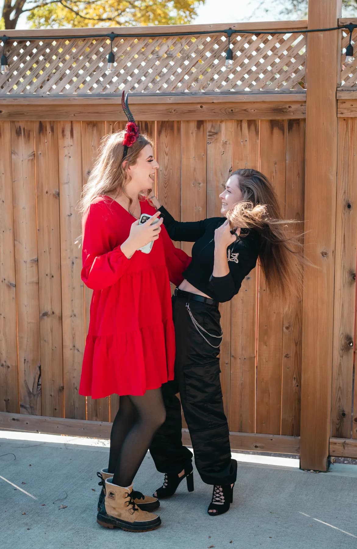 Two women dancing and posing in the outdoor courtyard at Jenna and Jake’s Halloween party.