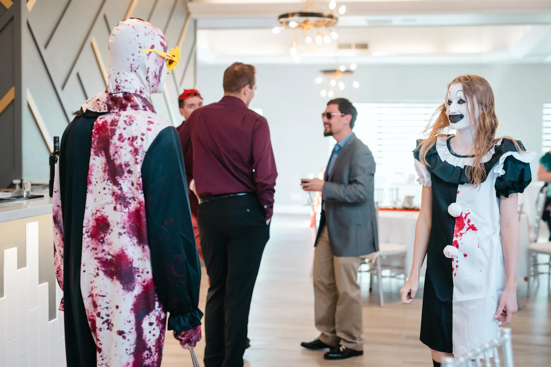 Costumed guests mingling near party tables at Jenna and Jake’s Halloween party.