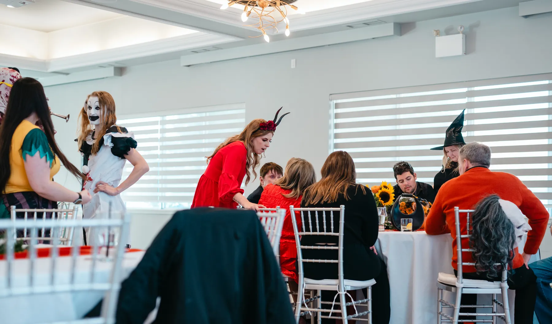 Costumed guests mingling near party tables at Jenna and Jake’s Halloween party.