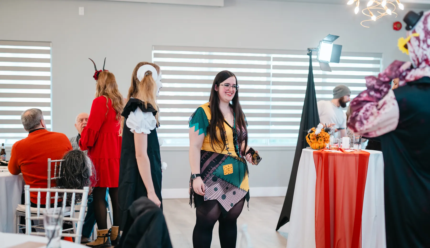 Guests posing and talking near Halloween decorations at Jenna and Jake’s Halloween party.
