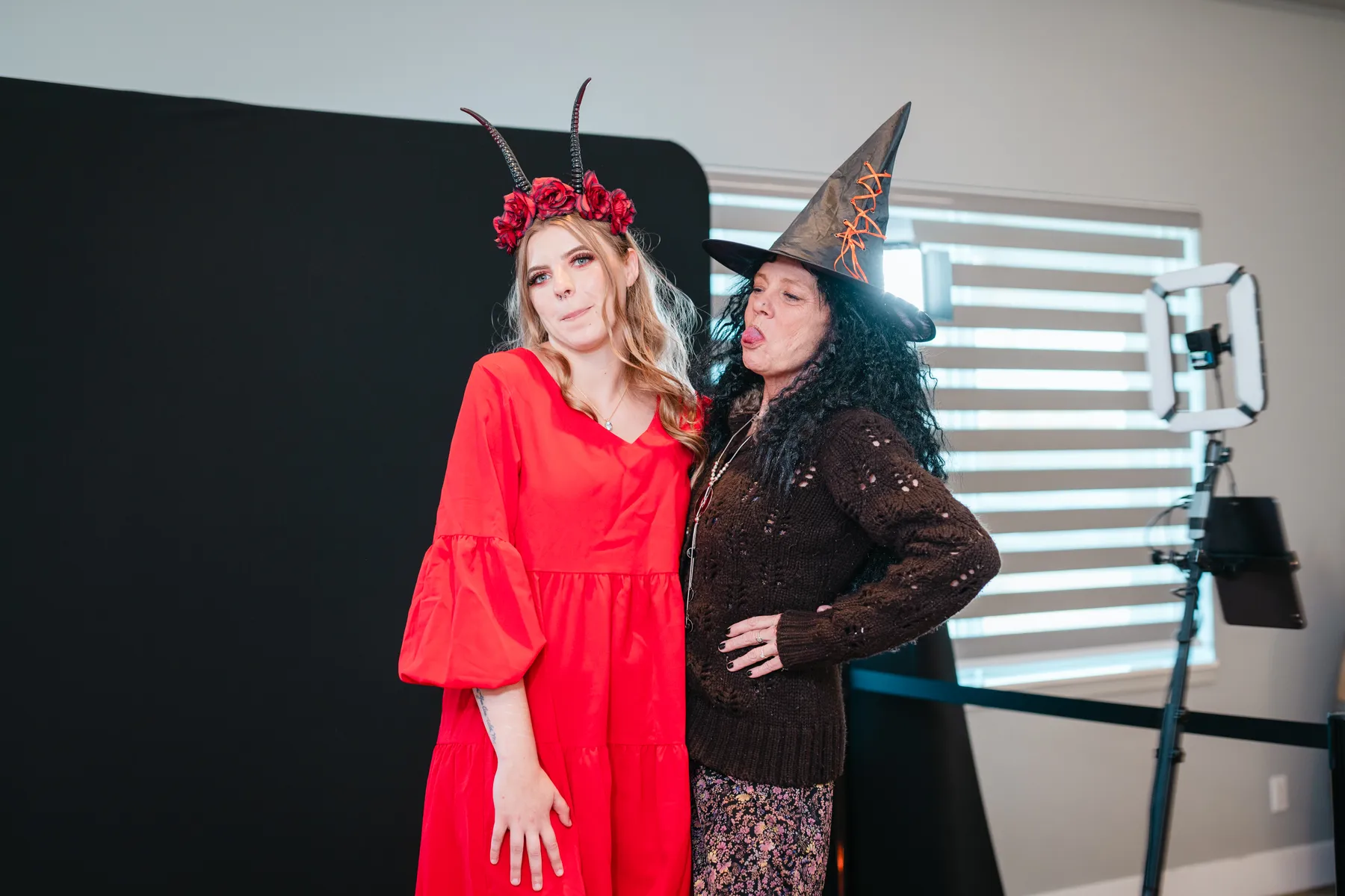 Costumed guests posing in front of a dark photo backdrop at Jenna and Jake’s Halloween party.