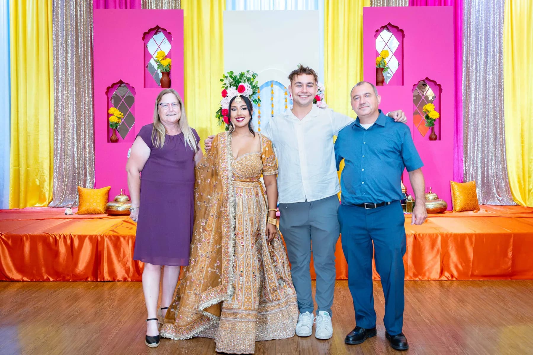 Guests posing together on the stage at Jessie and Erin’s Haldi celebration.