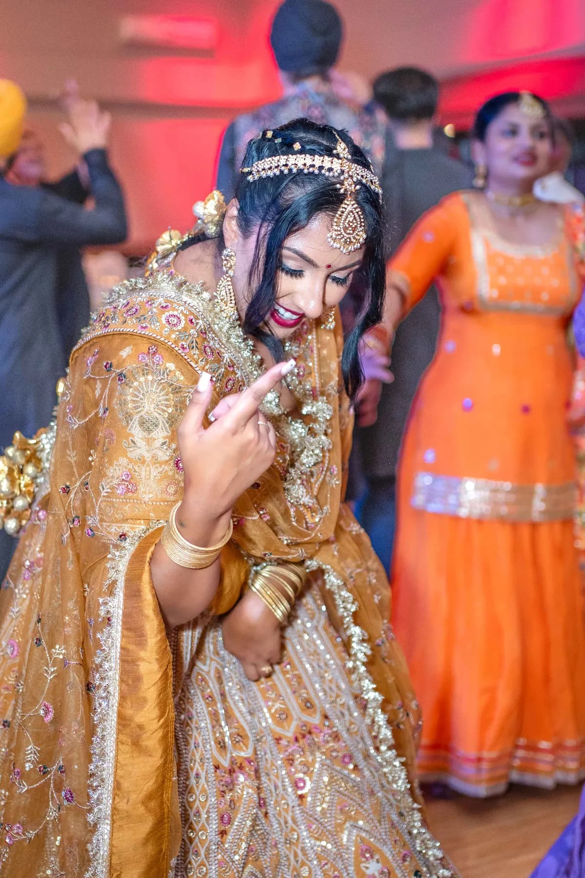 A woman dancing in a gold outfit at Jessie and Erin’s Haldi celebration.