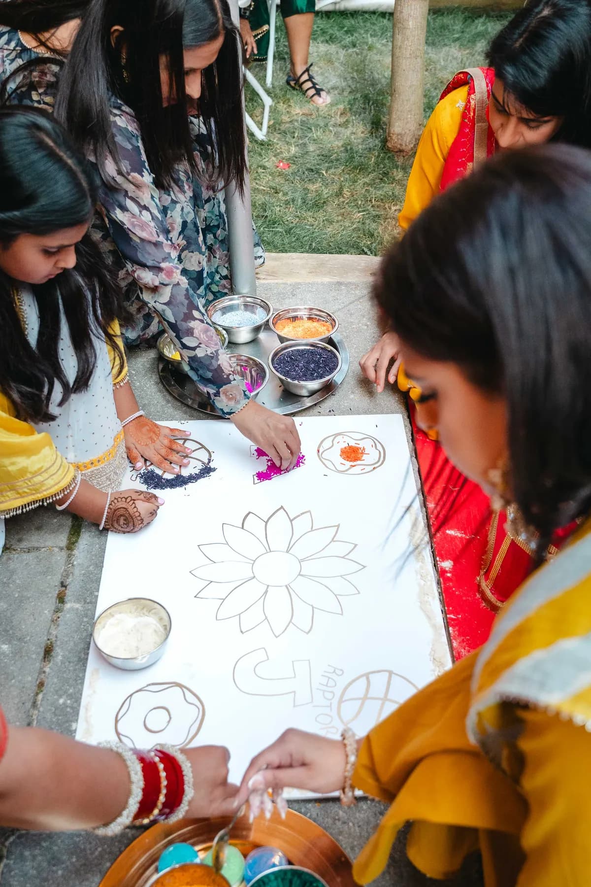 Hands creating colourful ceremonial artwork at Aaron’s Haldi celebration.