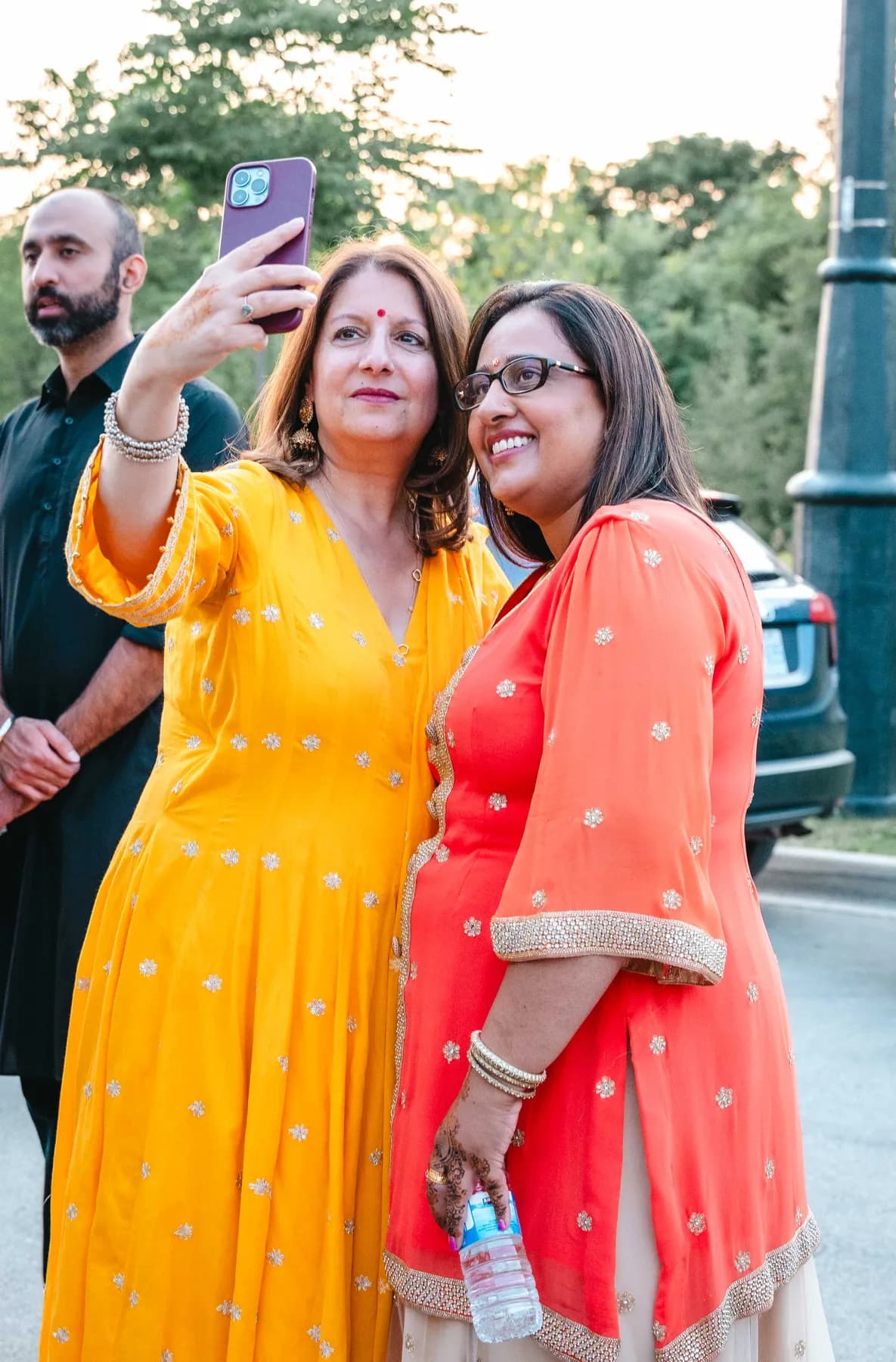 Women posing and taking photographs together at Aaron’s Haldi celebration.