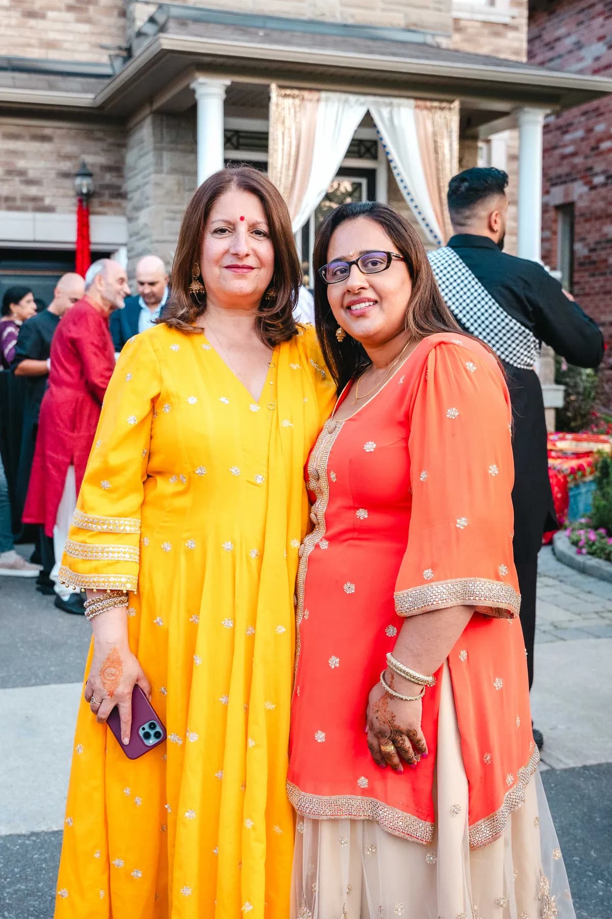 Women posing and taking photographs together at Aaron’s Haldi celebration.