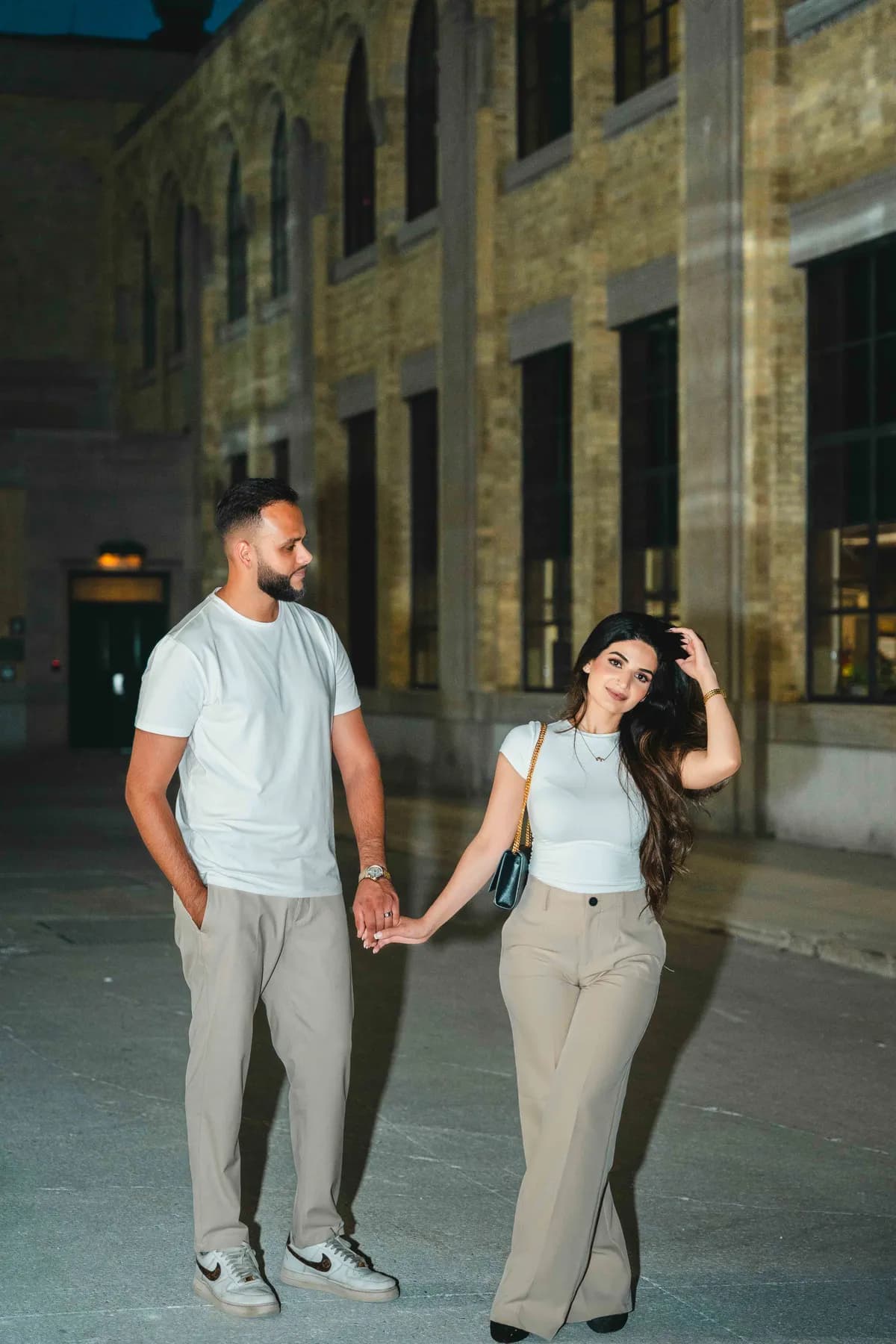 The couple holding hands outside a city building at A and F’s couples session.