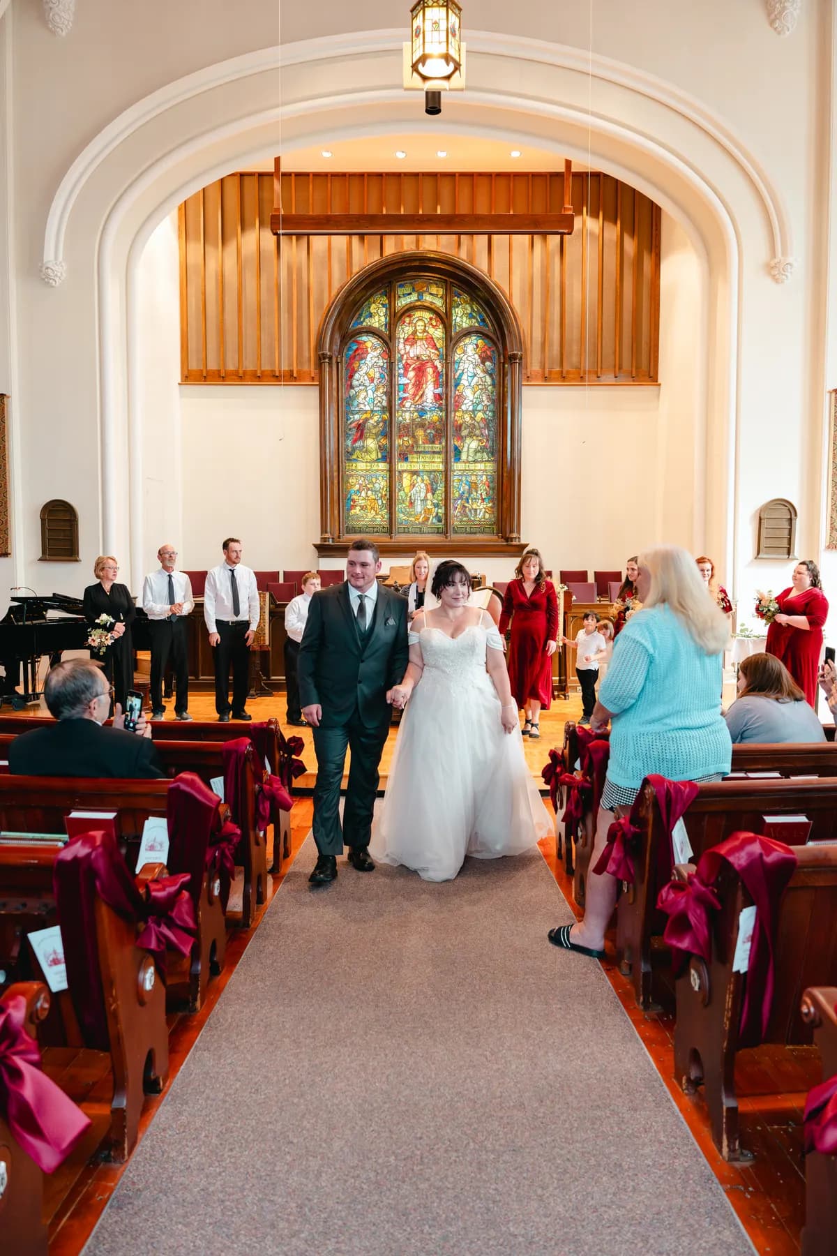 The couple walking down the church aisle after the ceremony at Kody and Jaz’s wedding.