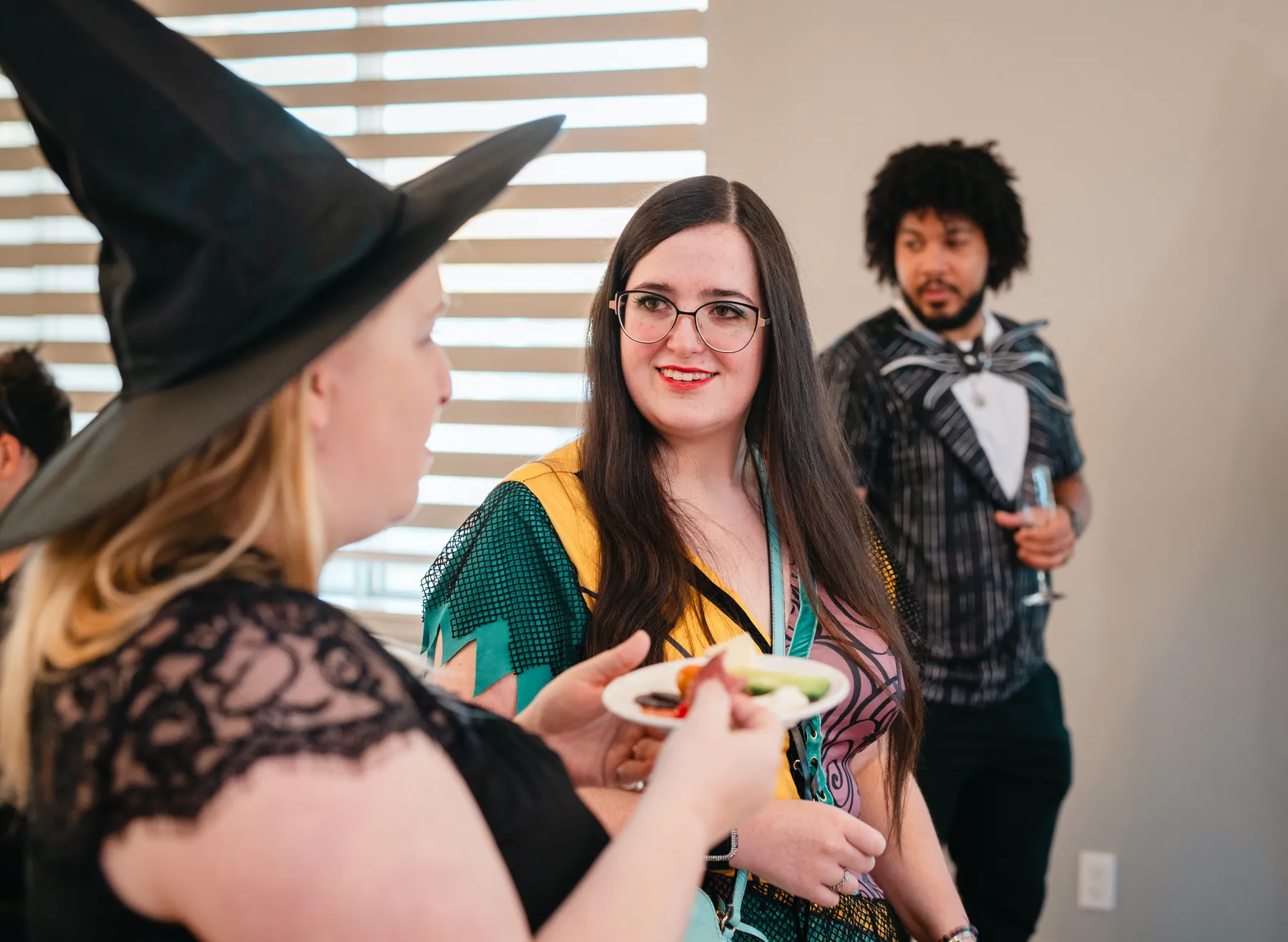 Costumed guests socializing around reception tables at Jenna and Jake’s Halloween party.