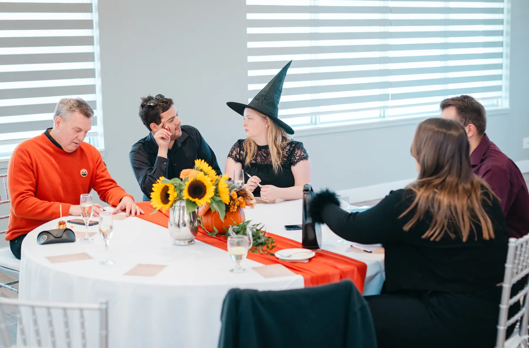 Costumed guests socializing around reception tables at Jenna and Jake’s Halloween party.