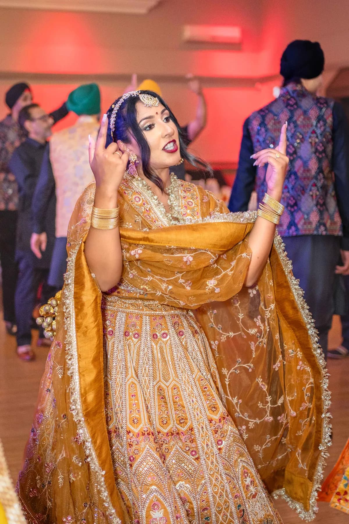 A woman dancing in a gold outfit at Jessie and Erin’s Haldi celebration.