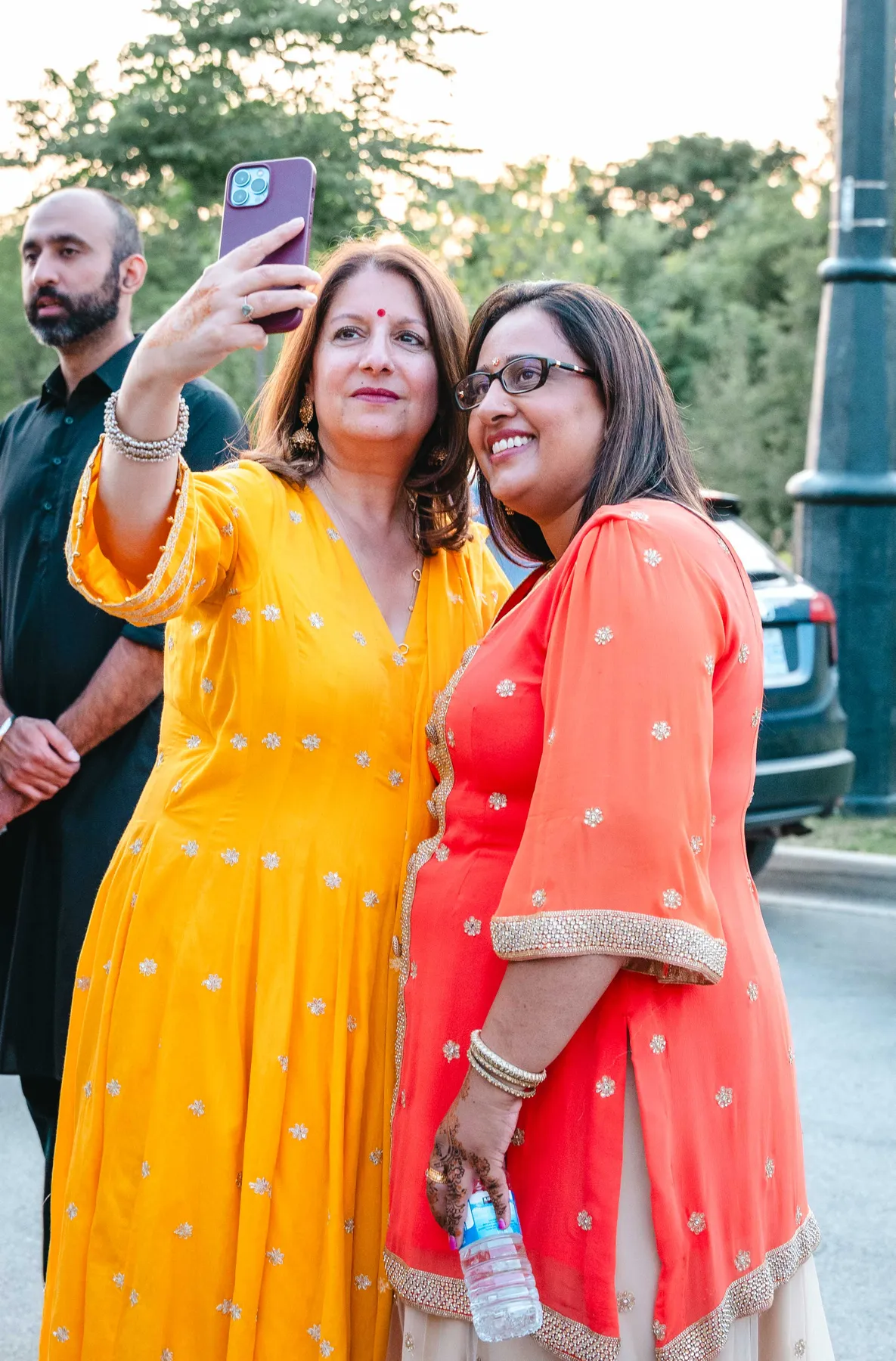 Women posing and taking photographs together at Aaron’s Haldi celebration.